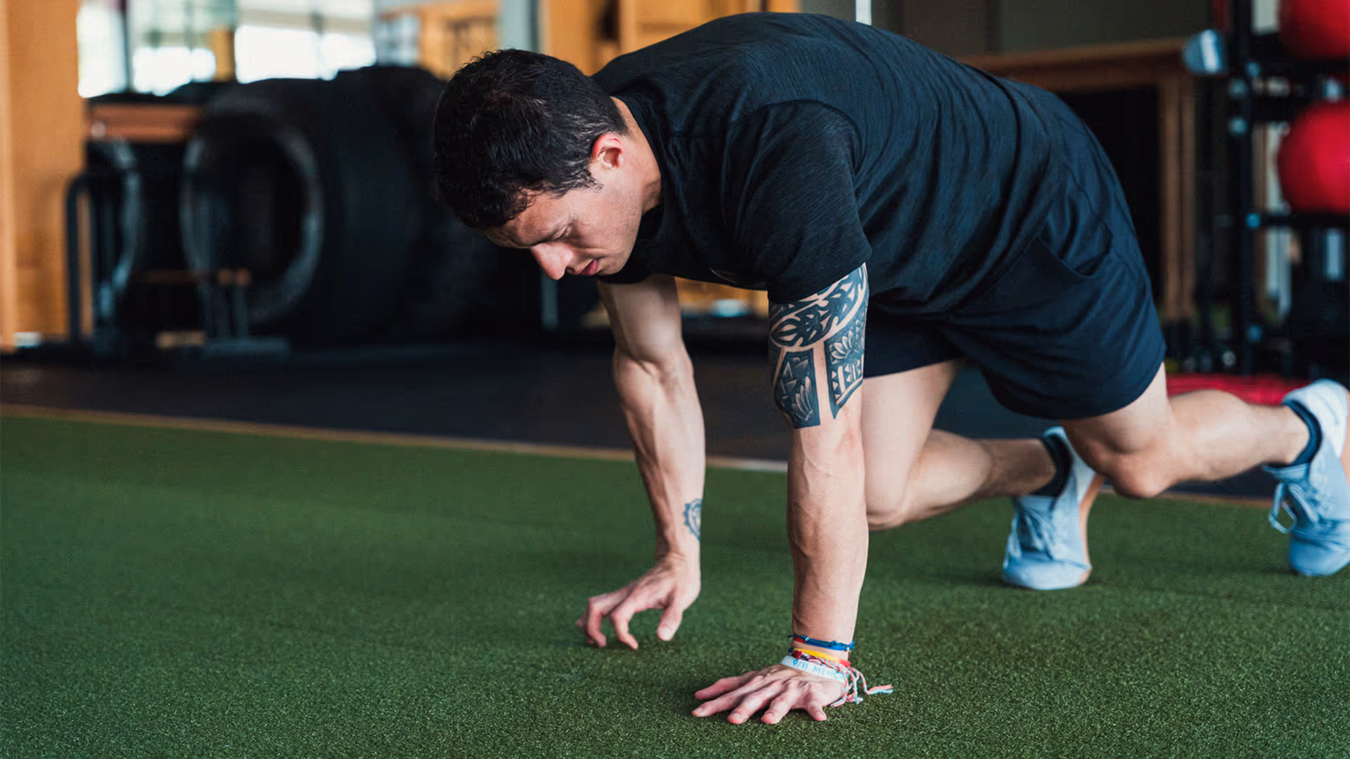 Ivan Salazar, Owner & Master Trainer, doing side gorilla crawls on green gym turf.