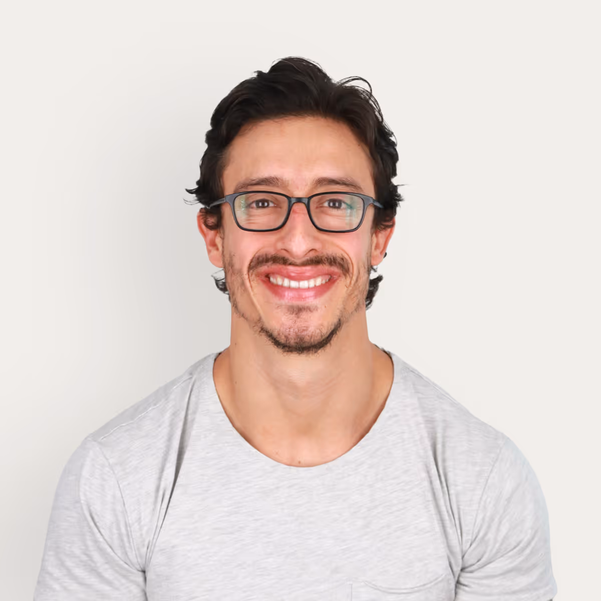 Headshot of Fabian Salazar, Owner & Master Trainer, smiling with dark hair and glasses wearing a light gray t-shirt against a plain white background.