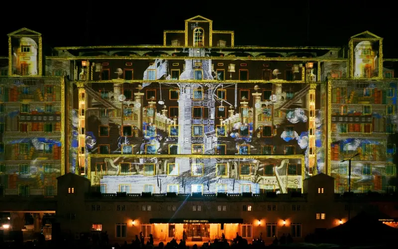 A building illuminated by colorful projection mapping on the facade, creating dynamic, interactive visual effects