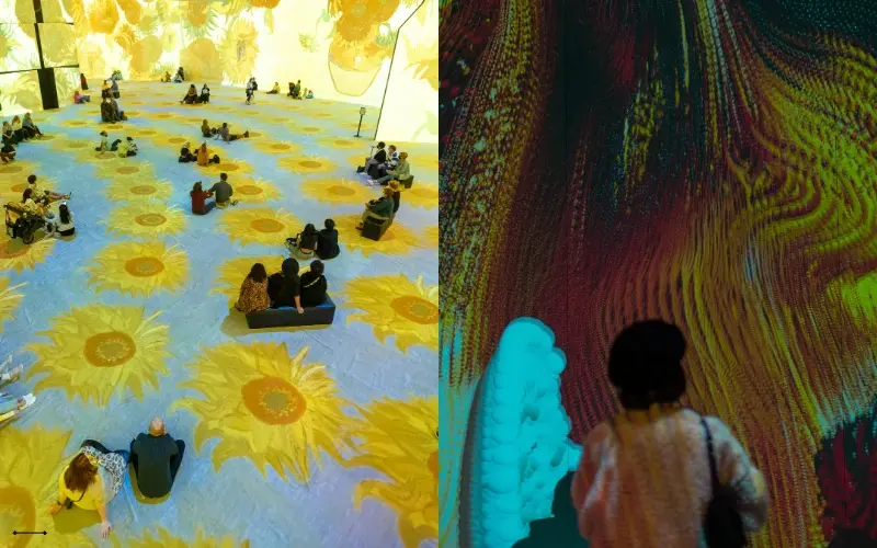 Visitors walking through a digital museum exhibit where animated artwork is projected onto the floors and walls, creating a fully immersive visual experience