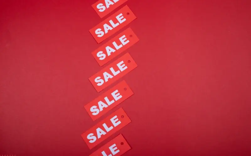 Red sale tags lined up on a red background, representing flash sales and limited-time ticket offers for events.