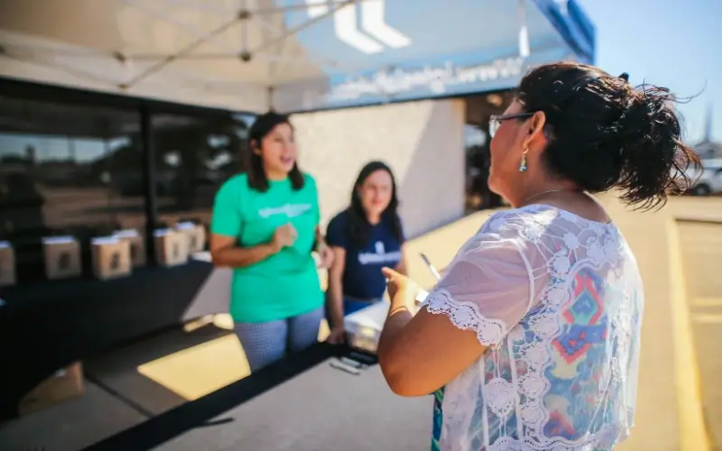 Attendee speaking with event staff at an outdoor check-in booth, illustrating how group and bundle ticket strategies attract more attendees.