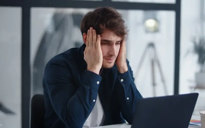 Man looking stressed at a laptop, representing common mistakes to avoid in virtual events.
