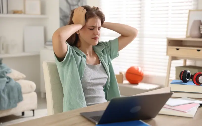 Student experiencing overwhelm during a virtual education fair, highlighting the challenge of navigating too many university booths online.