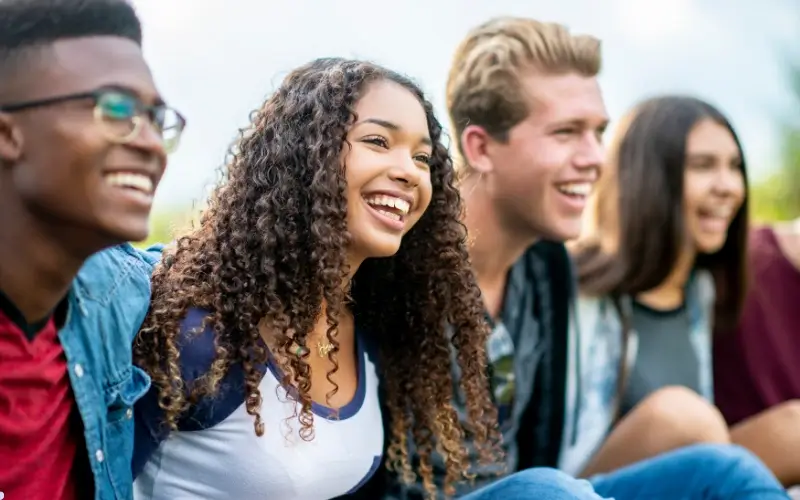 Teenagers laughing together outdoors, reflecting fun icebreaker questions for teens that encourage easy, playful interaction.