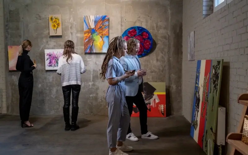 People exploring artwork in a physical gallery, illustrating the in-person exhibition experience.