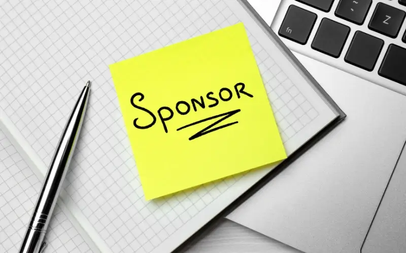 Sticky note labeled “Sponsor” on a desk, representing sponsorship planning and outreach for events.