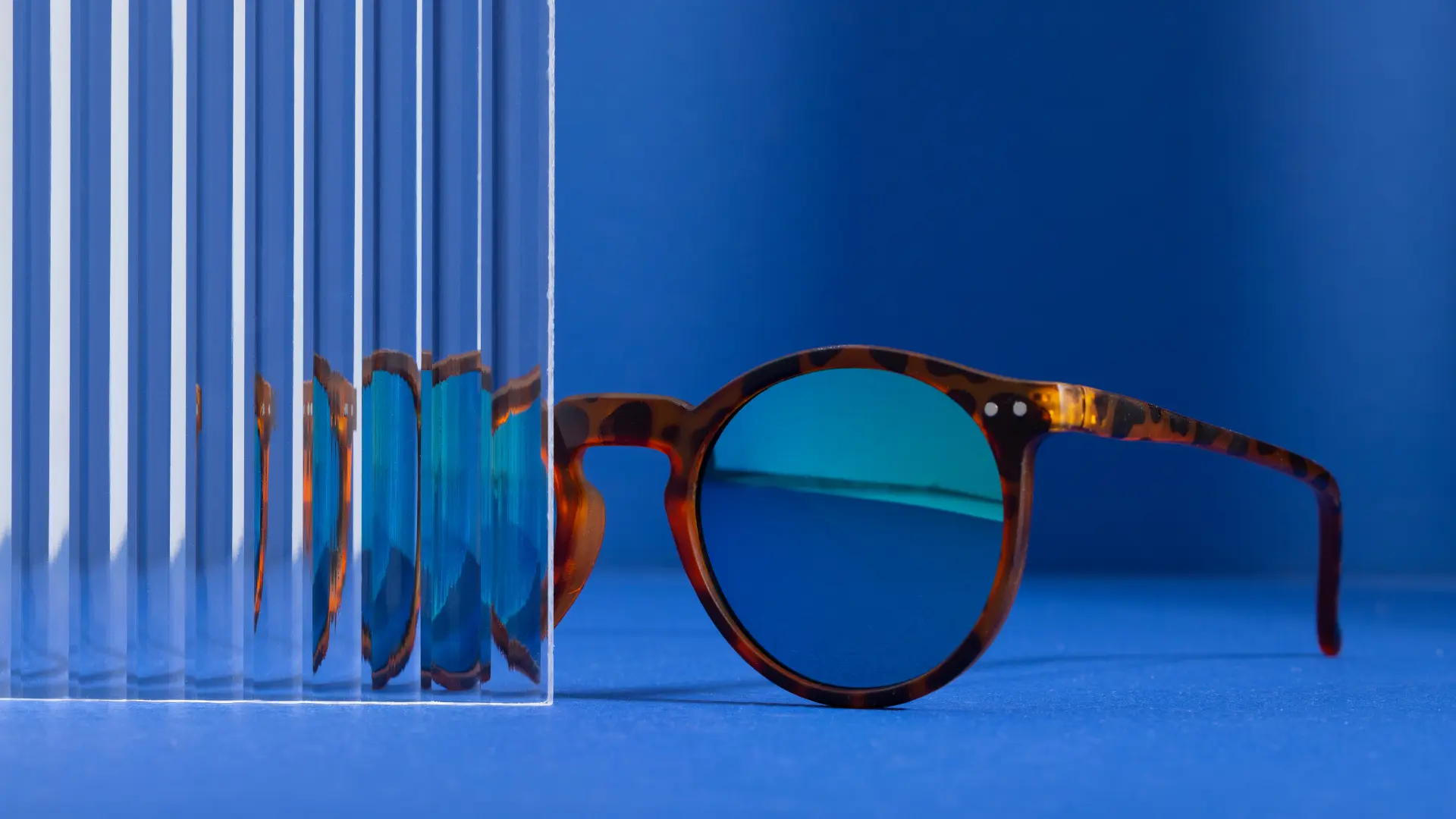 Blue light glasses placed beside a translucent panel on a desk.