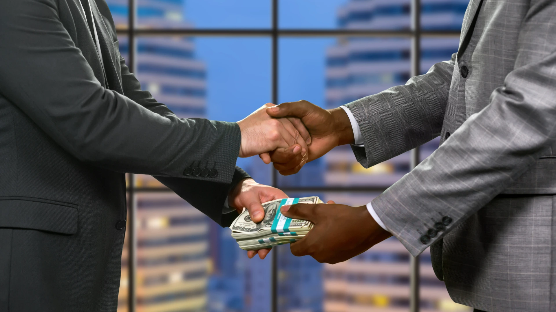 Two business professionals shaking hands while exchanging a stack of cash, representing financial event support.