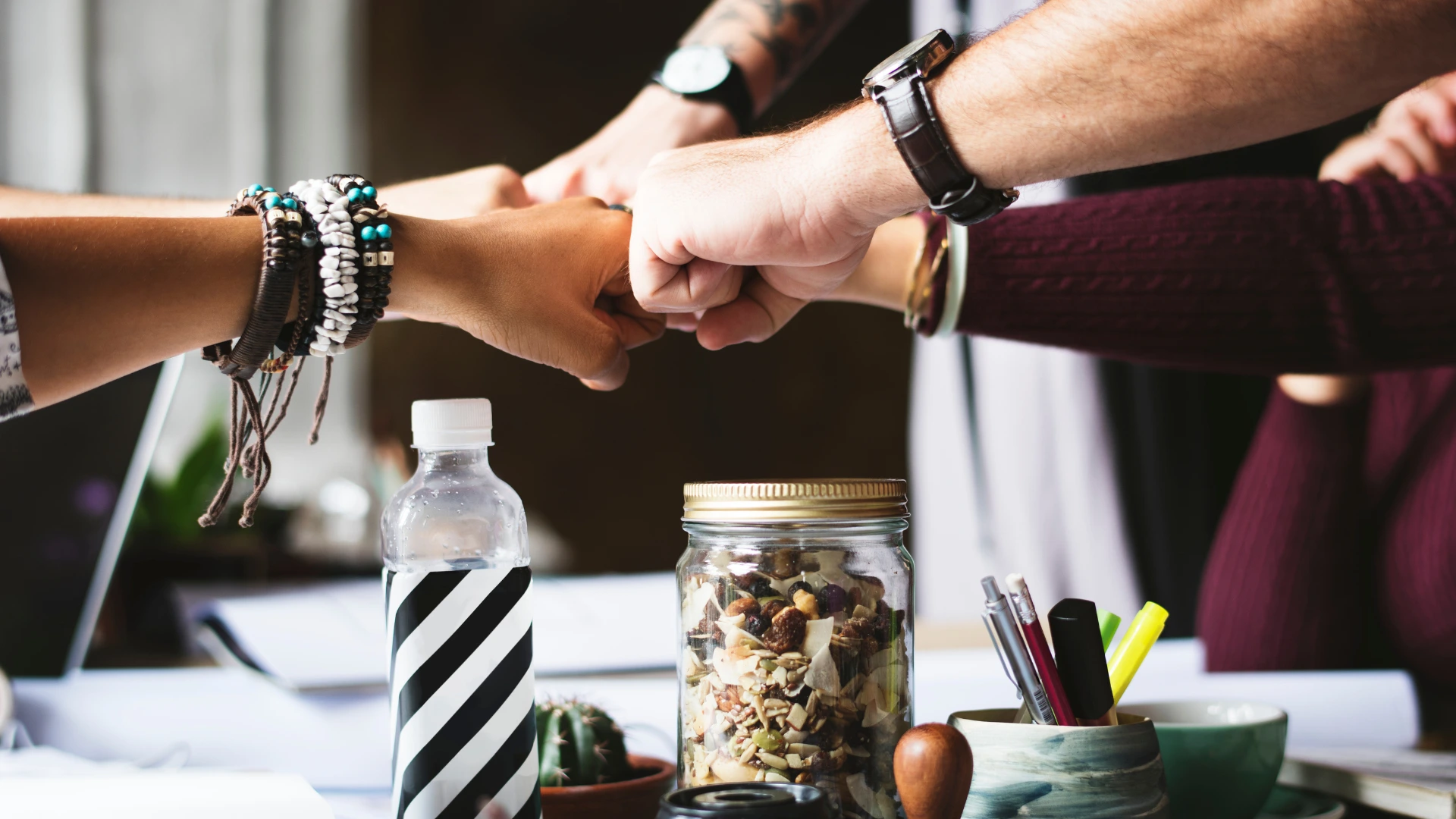 Team members bumping fists over a table with supplies and refreshments, symbolizing in-kind partnership contributions.