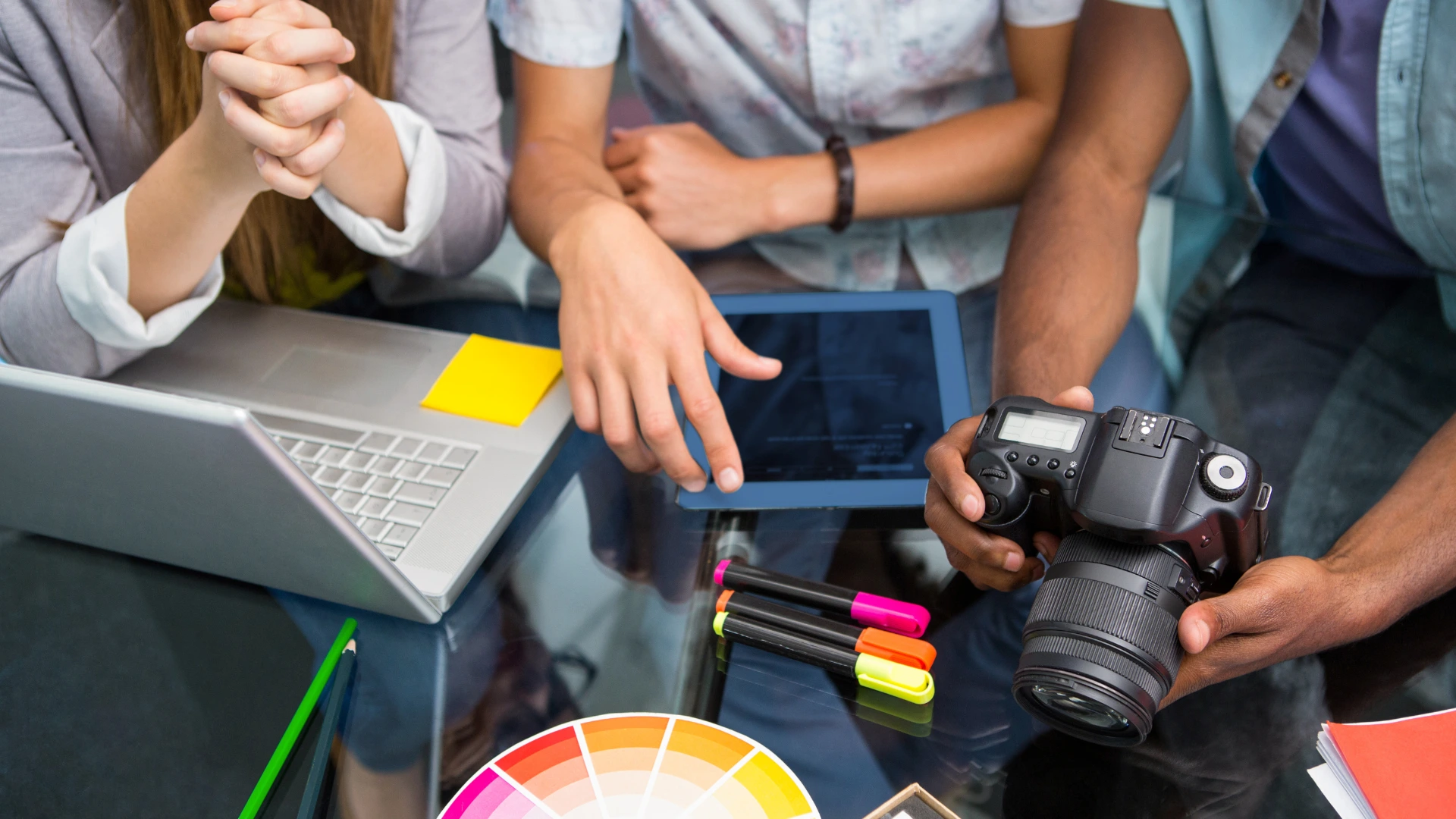 Creative team reviewing photos on a camera and tablet, illustrating media partnership and promotional coverage.