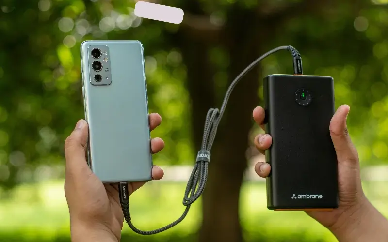 Sponsor-branded portable power bank charging a smartphone at an outdoor event.