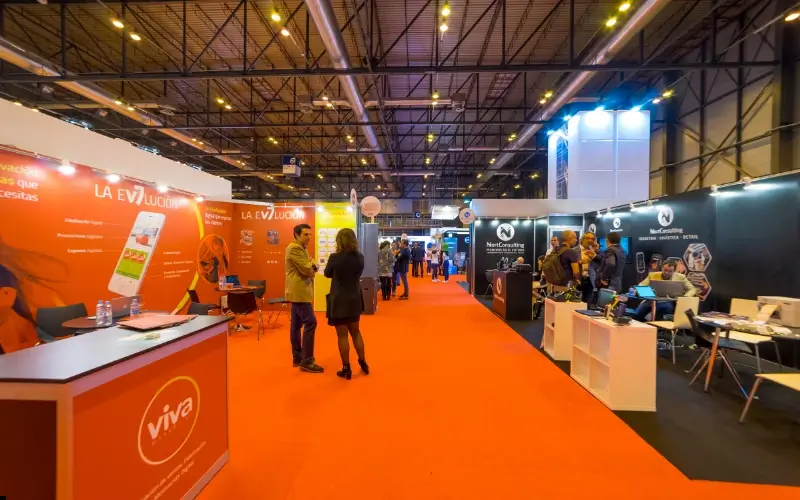 Exhibition hall with multiple employer booths where recruiters and attendees interact during a career fair.