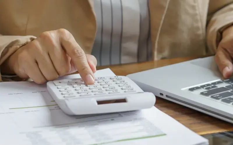 Person using a calculator next to a laptop, symbolizing event sponsorship ROI calculation and measuring sponsorship costs and returns.