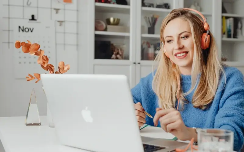Woman wearing headphones participates in a webinar from her laptop at home.