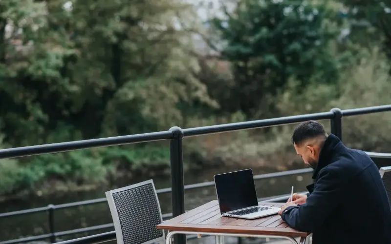 Remote worker using a laptop while working alone at an outdoor table.