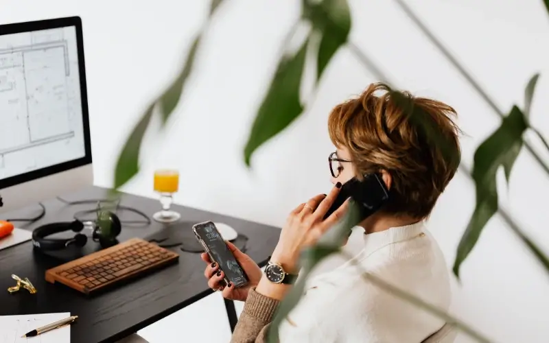 Remote employee working from home while speaking on the phone at a desk.