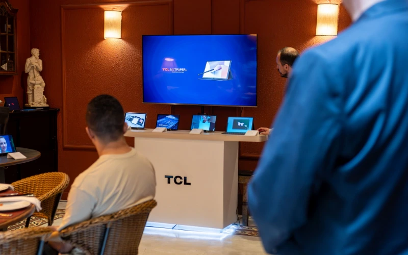 Product demonstration at a TCL event with attendees viewing a large display screen.