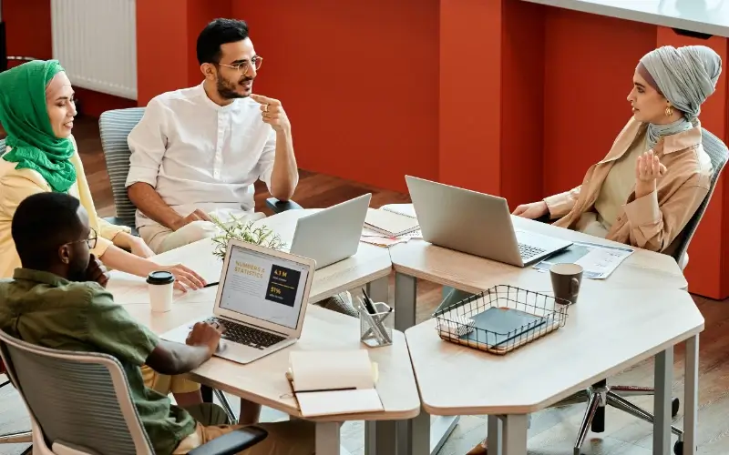 Four colleagues discuss ideas together around a table during a collaborative roundtable session.