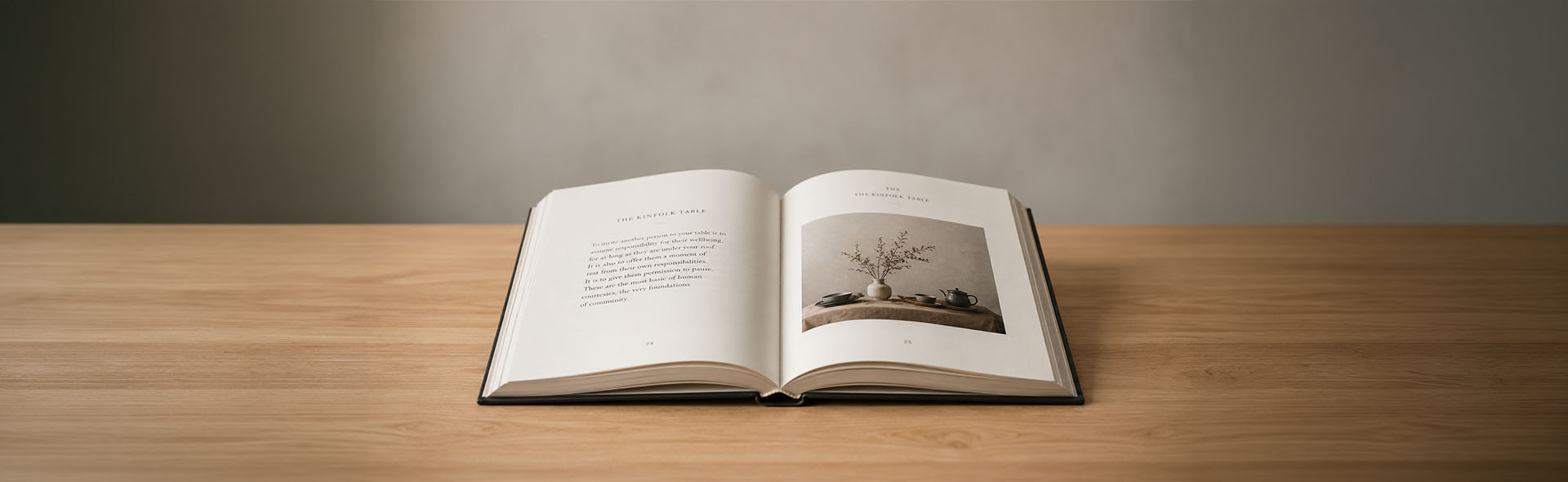 Open hardcover book showing professional interior layout and typesetting on a wooden desk — book design services