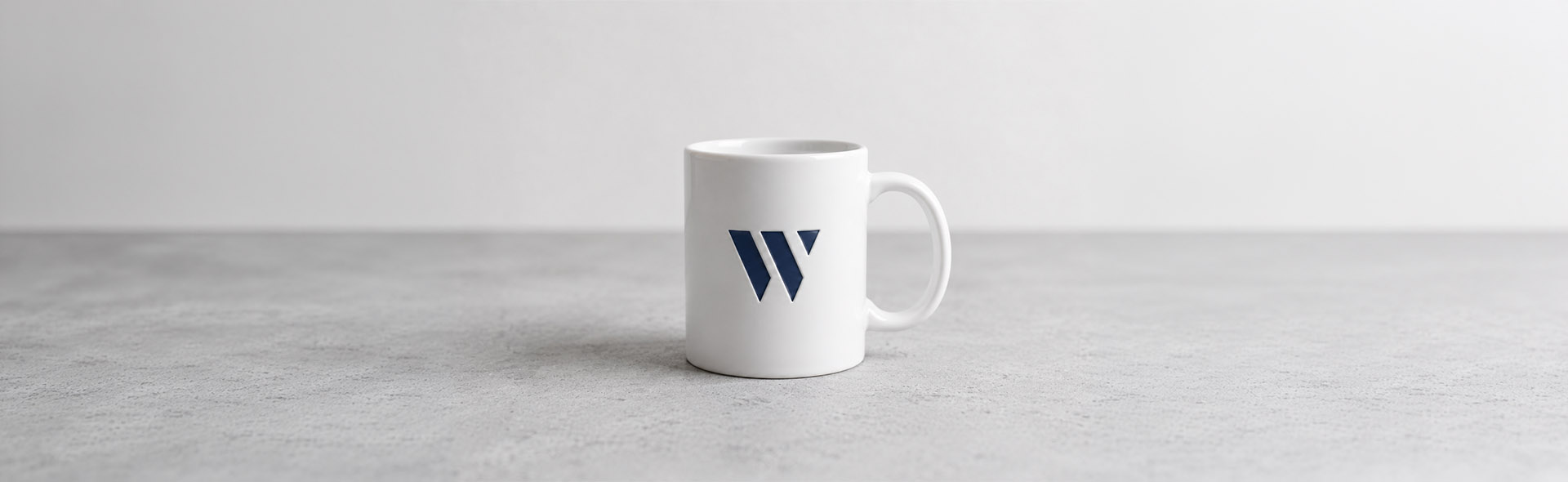 White ceramic mug with a navy logo mark — professional logo and brand identity design