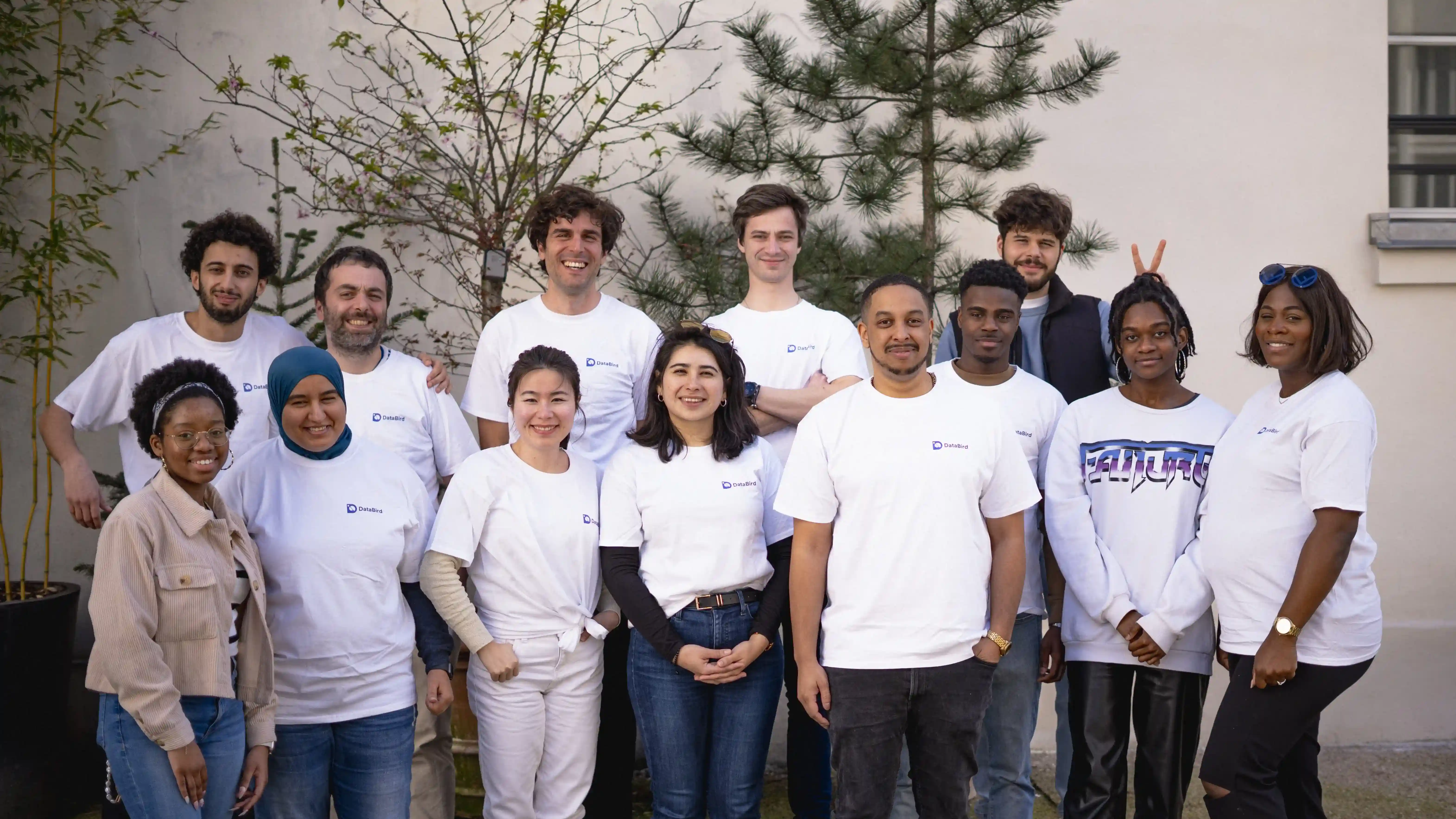 Équipe diversifiée en t-shirts blancs pose ensemble à l'extérieur.