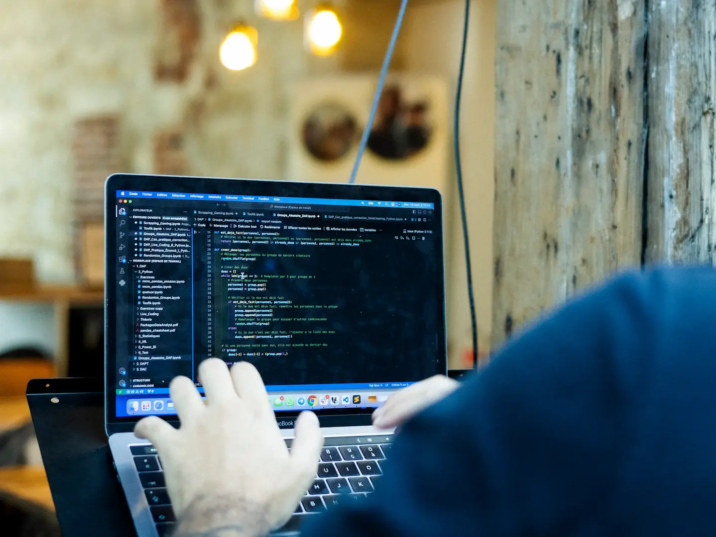 programmeur en formation data et ia tape sur un ordinateur portable affichant du code dans un espace coworking bois
