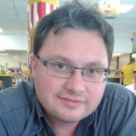 Un homme en chemise avec des lunettes, souriant