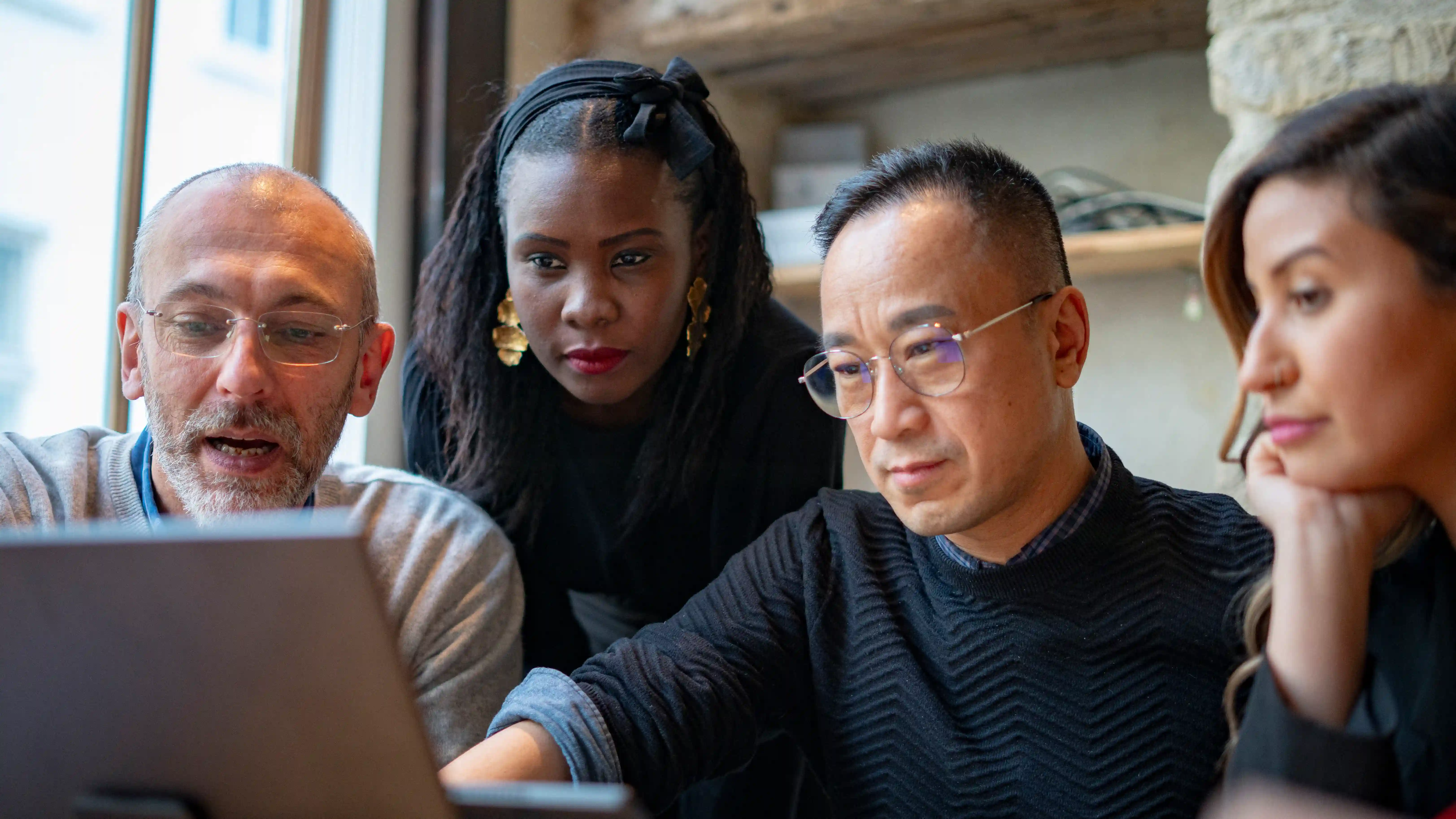 Quatre professionnels autour d'un ordinateur portable discutent d'un projet data et intelligence artificielle.