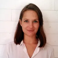 Femme en chemise blanche, sourire léger, portrait devant fond clair.
