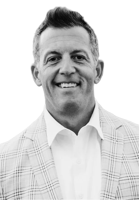 Smiling man with short hair wearing a white shirt and a light plaid blazer.