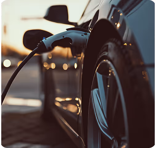 Electric car plugged into a charging station during sunset.