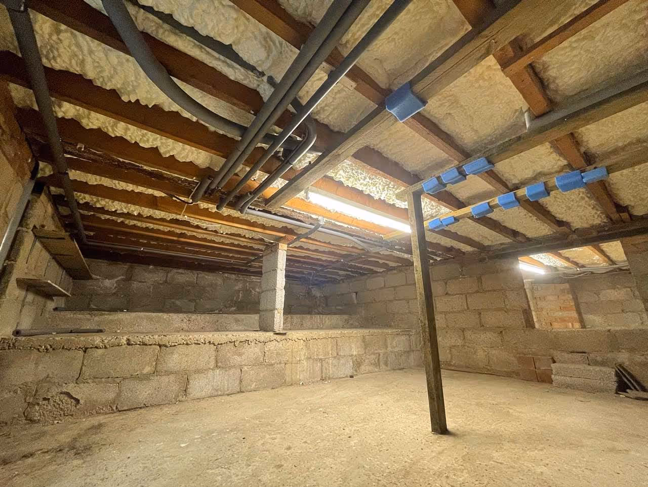 Underside of flooring beams that have been insulated by spray foam