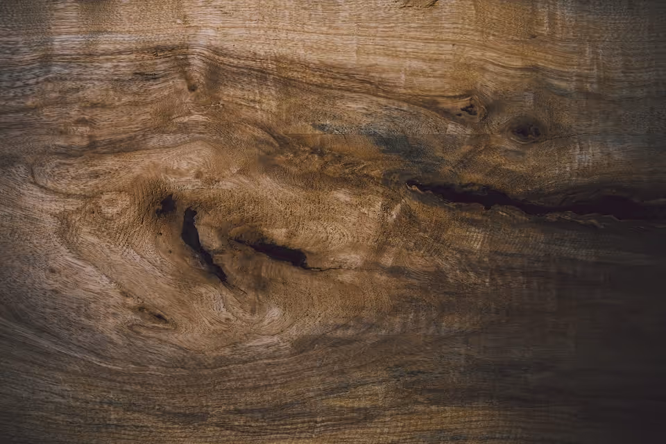 A photograph of dark brown wood grain with swirling patterns and knots.