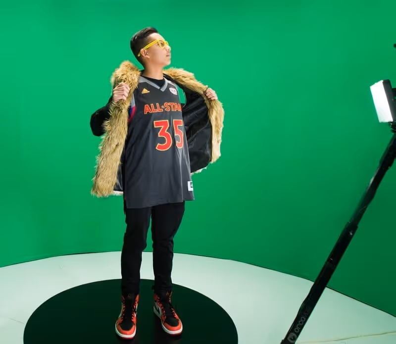 Man on a 360 photo booth in front of a green screen backdrop