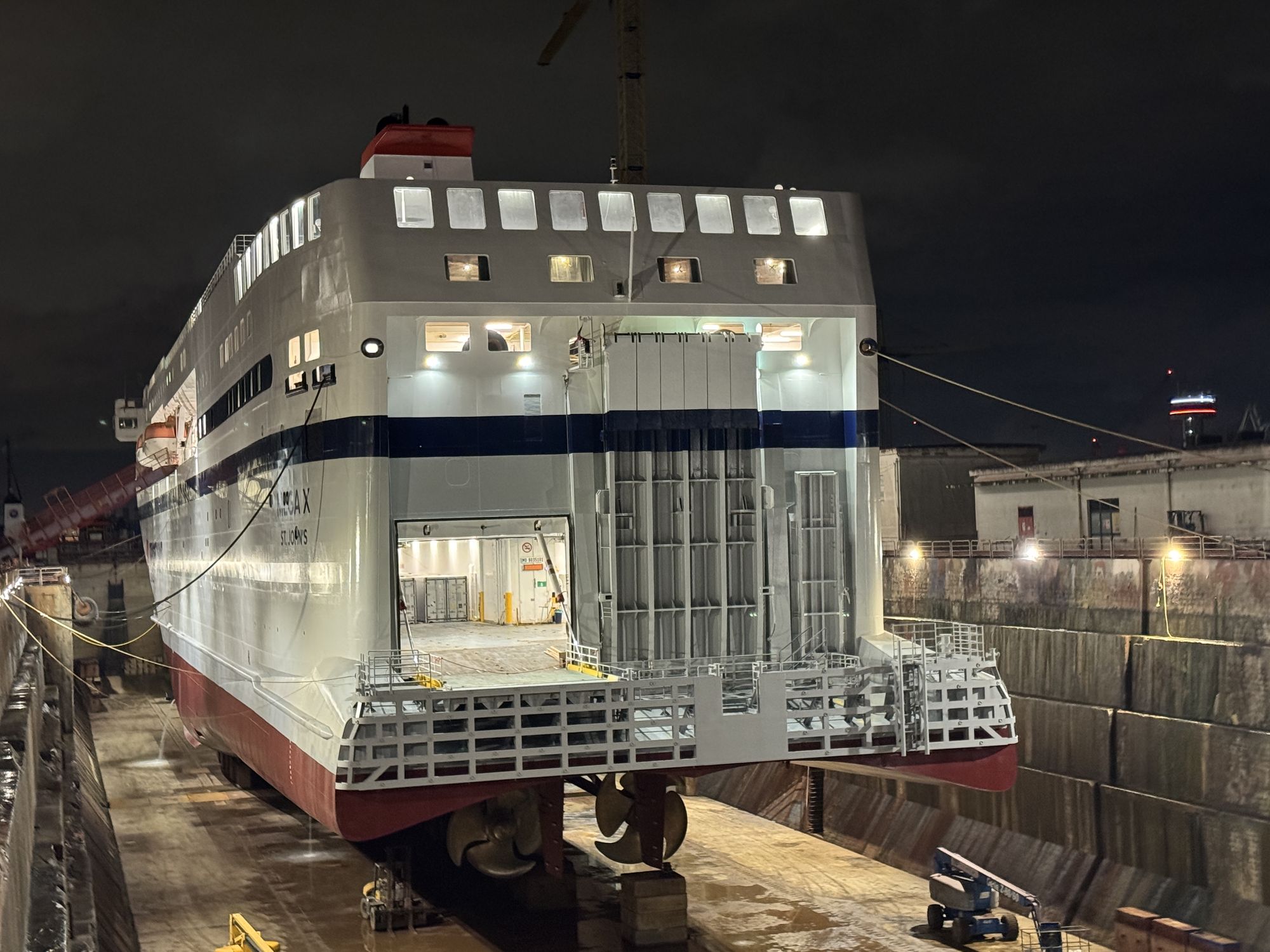 MEGA X's stern in dry dock at night, name visible.