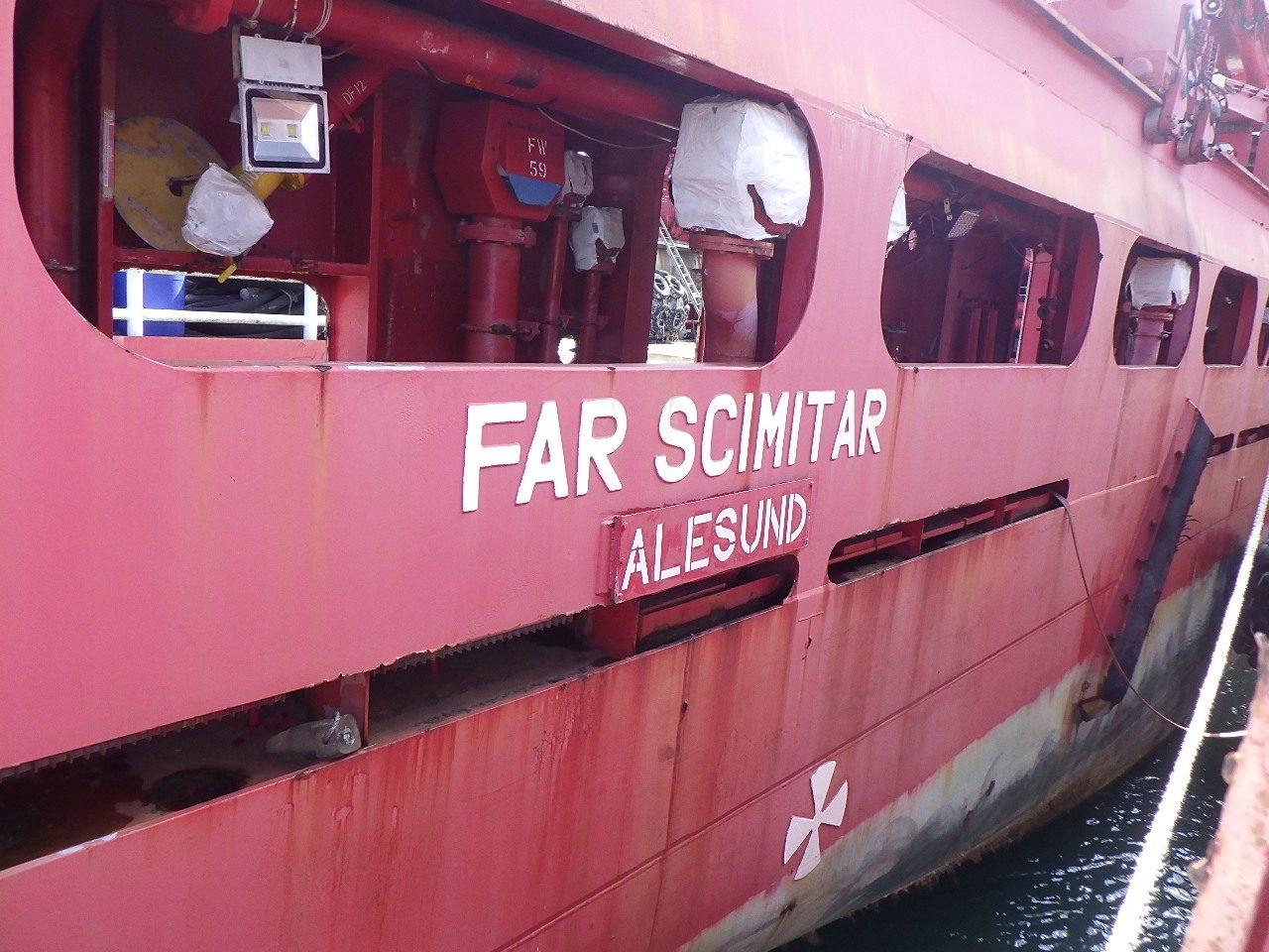 Close-up of the 'Far Scimitar, Ålesund' hull markings before renaming to Oceanicasub XV, showing a weathered, laid-up hull.