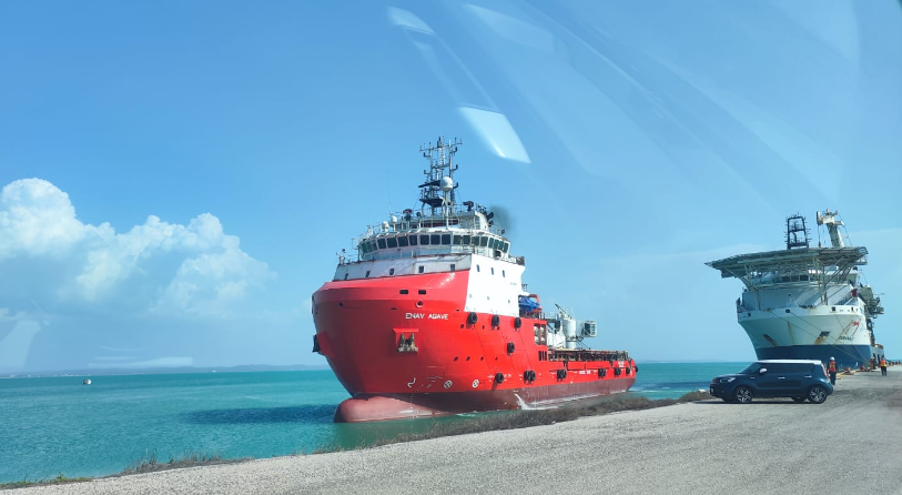 Red-hulled offshore support vessel underway near shore, prior to acquisition and renaming