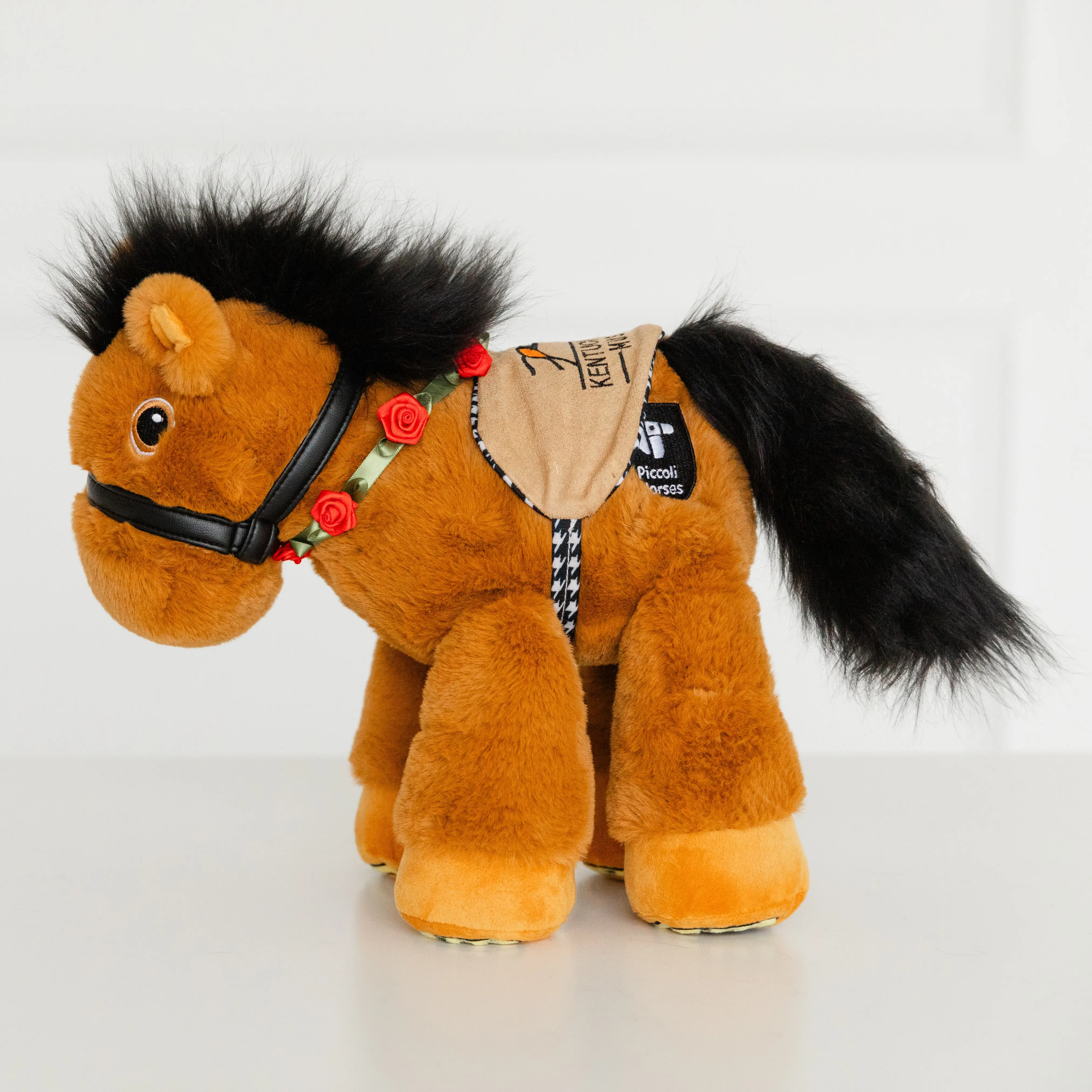 The G.O.A.T, affectionately known as Billy, has luxuriously soft chestnut faux fur because chestnut Thoroughbreds hold the record for the most wins. Embroidered eyes and gold shoes adorn the bottom of this limited edition horse's feet. Stunning black vegan leather face halter and saddle. 14 inches (35.5cm) — Ages 3+