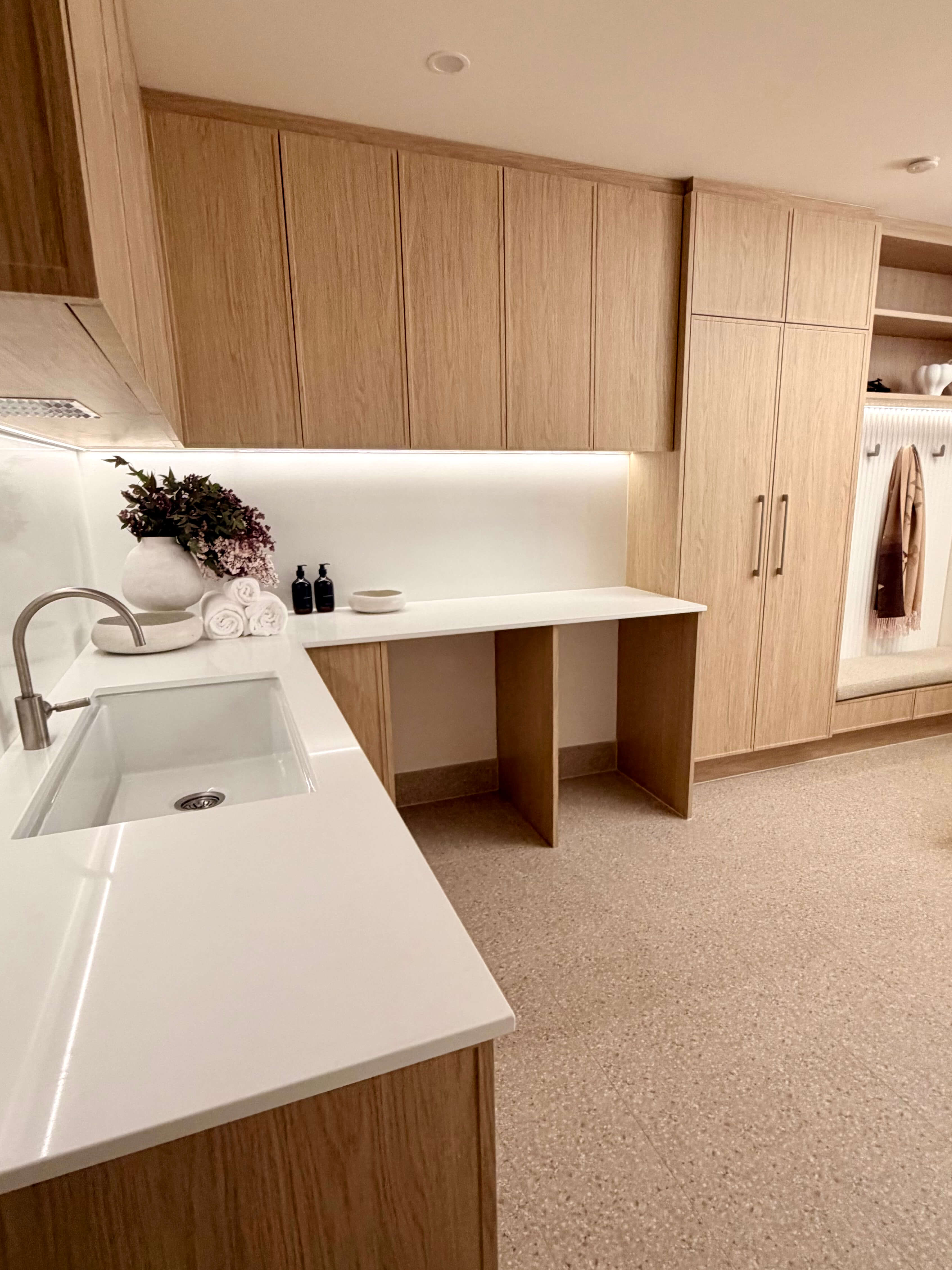 Luxury laundry mudroom designed with custom joinery, natural stone benchtops and practical family-friendly organisation.