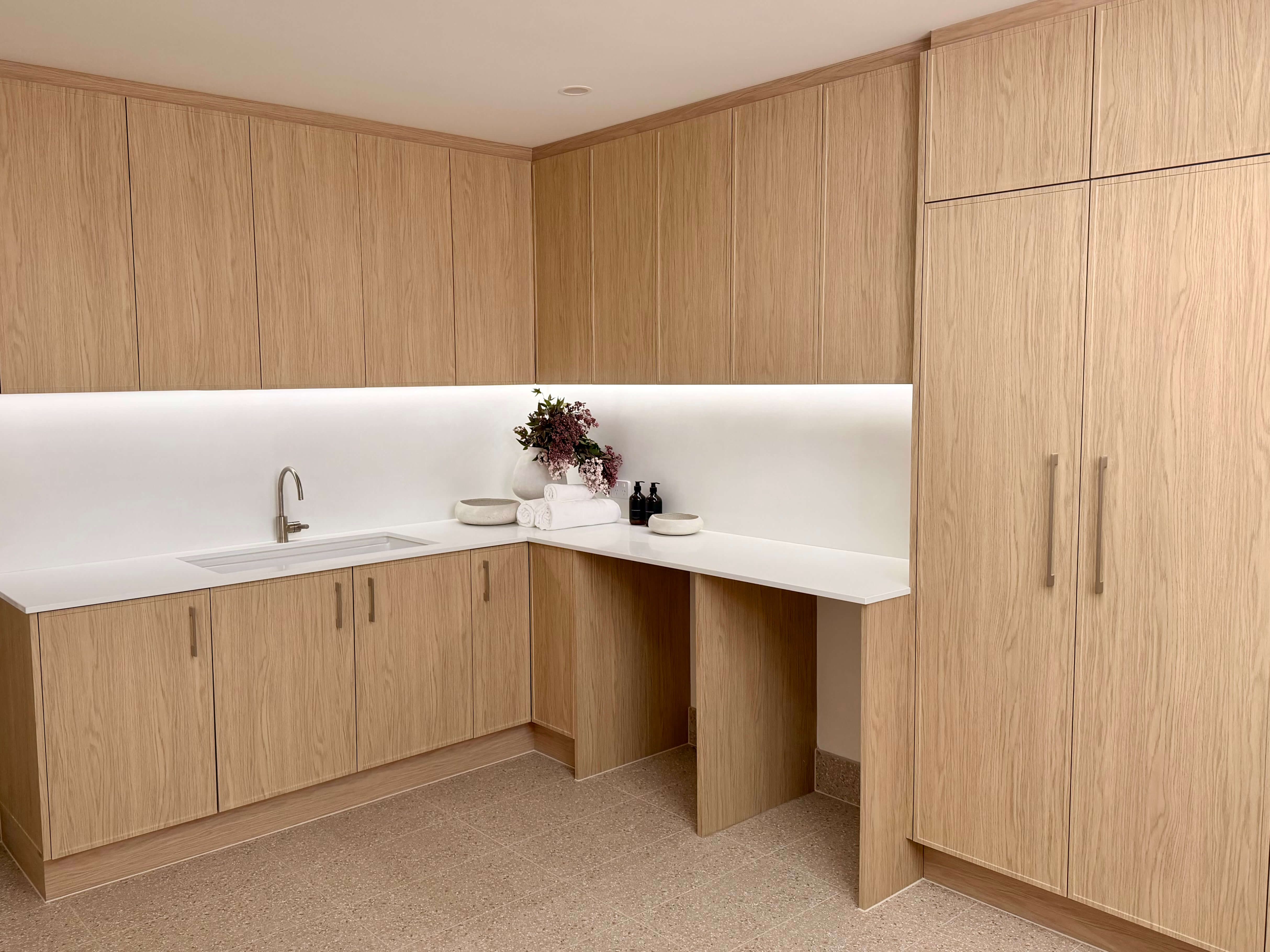 Luxury laundry design with custom joinery, natural stone benchtops and integrated lighting for a timeless finish.