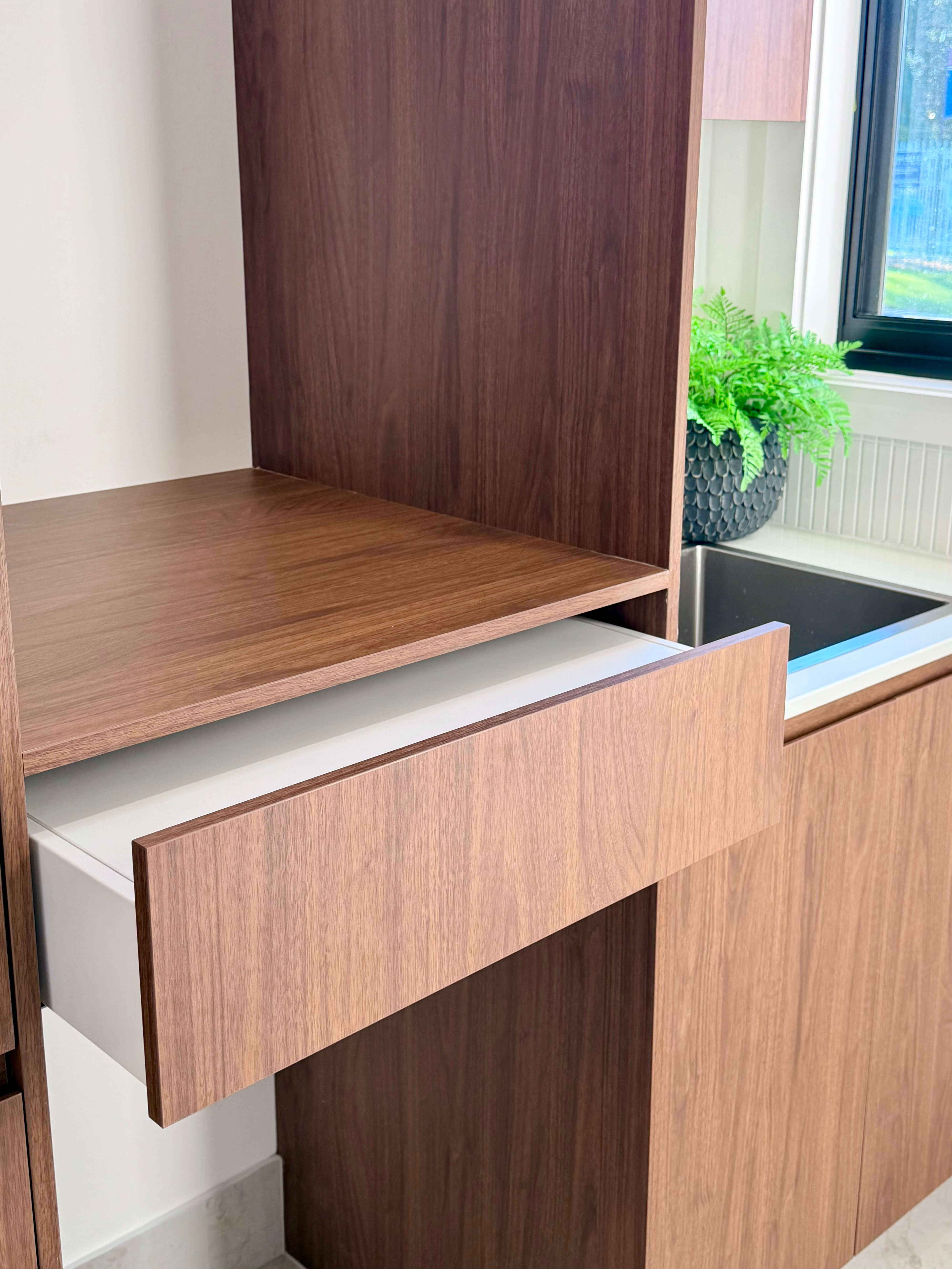 Luxury laundry featuring custom dark walnut cabinetry, bespoke joinery and functional storage solutions.