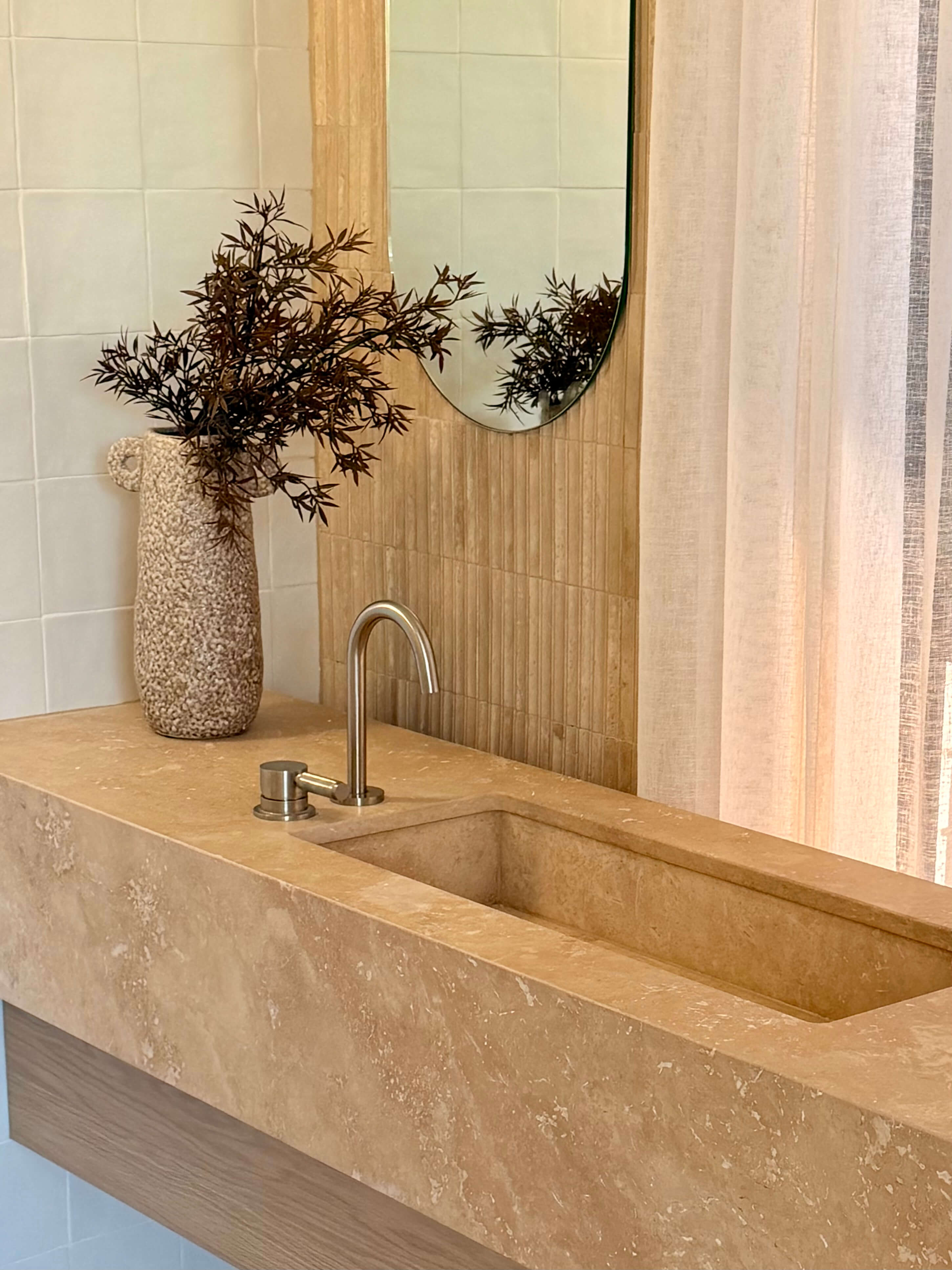 Custom bathroom vanity with a warm mineral stone sink, matching benchtop and bespoke joinery.