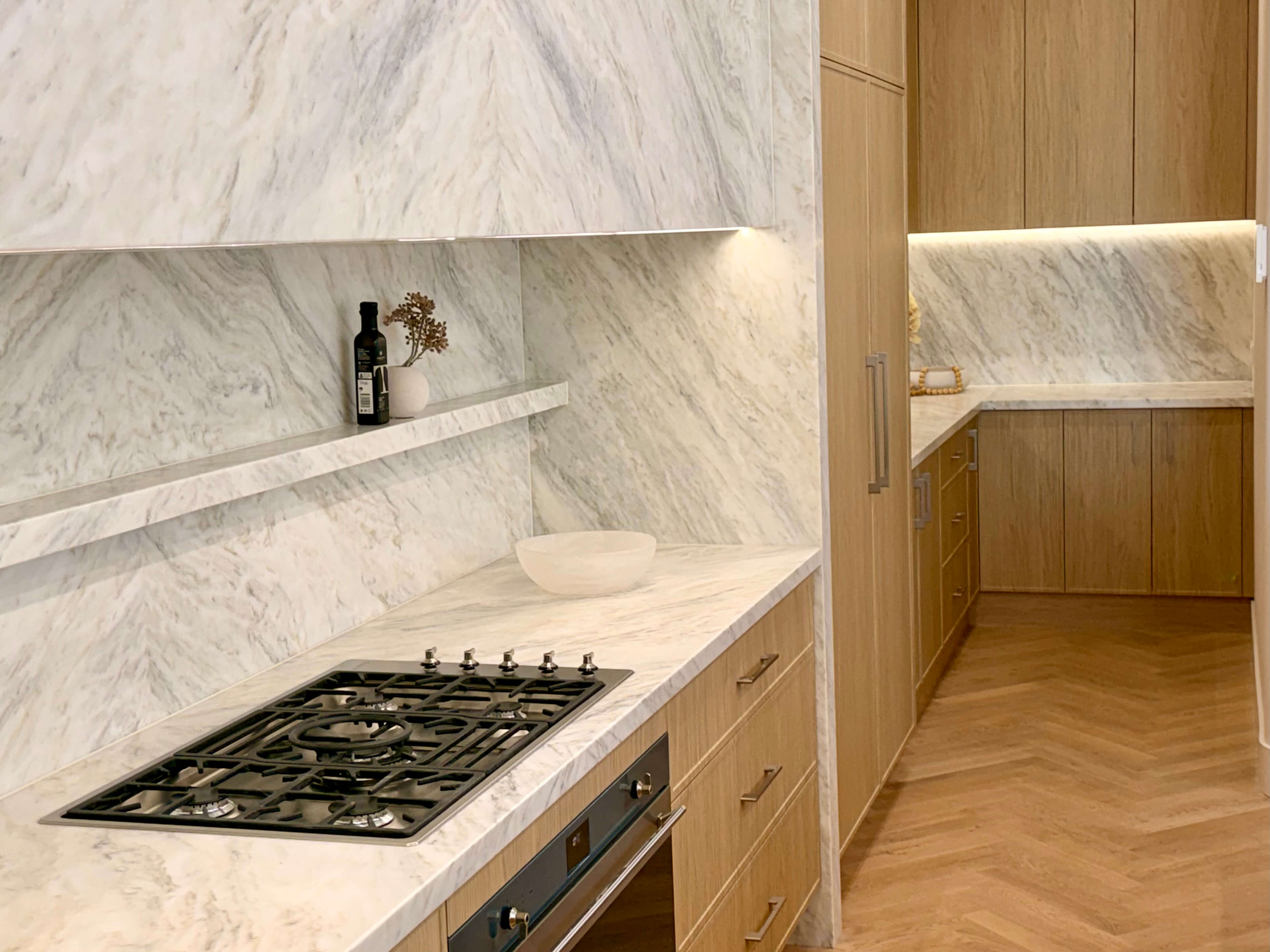 Luxury custom kitchen with natural stone benchtops, integrated lighting and premium bespoke joinery.