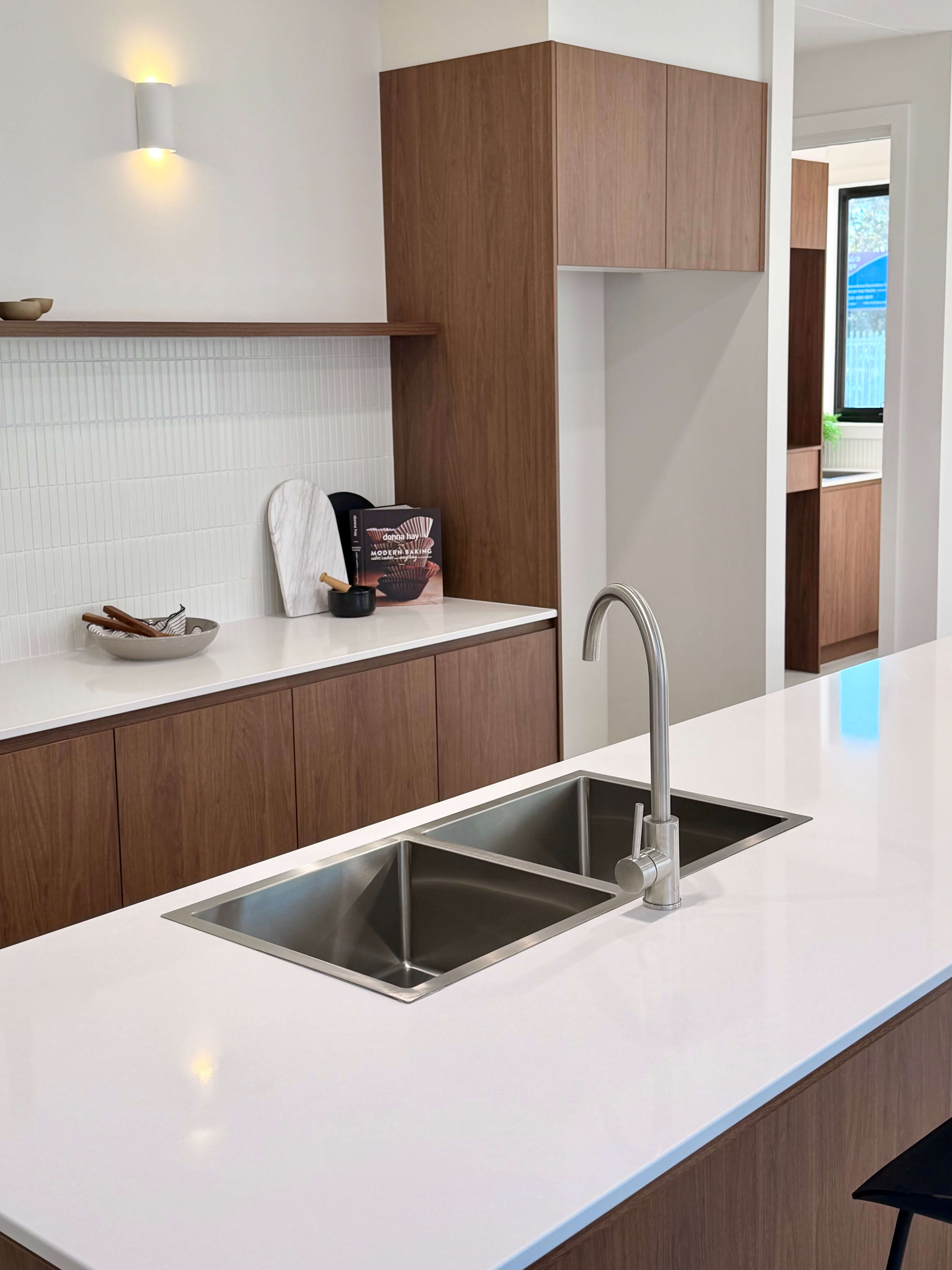 Open-plan kitchen with custom walnut cabinetry, natural stone benchtops and premium bespoke joinery.