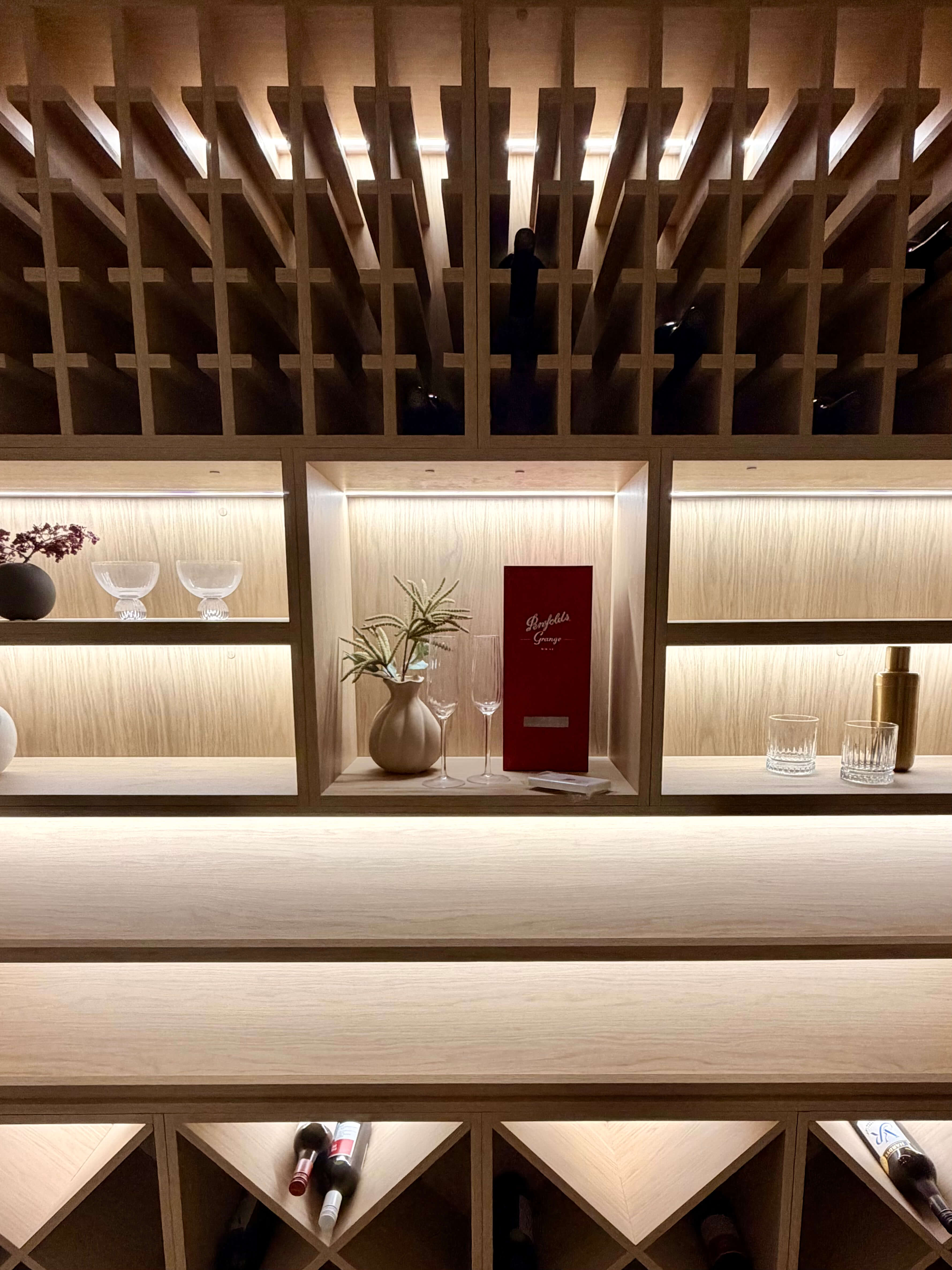 Luxury wine cellar featuring custom cabinetry, backlit shelving and elegant wine storage.