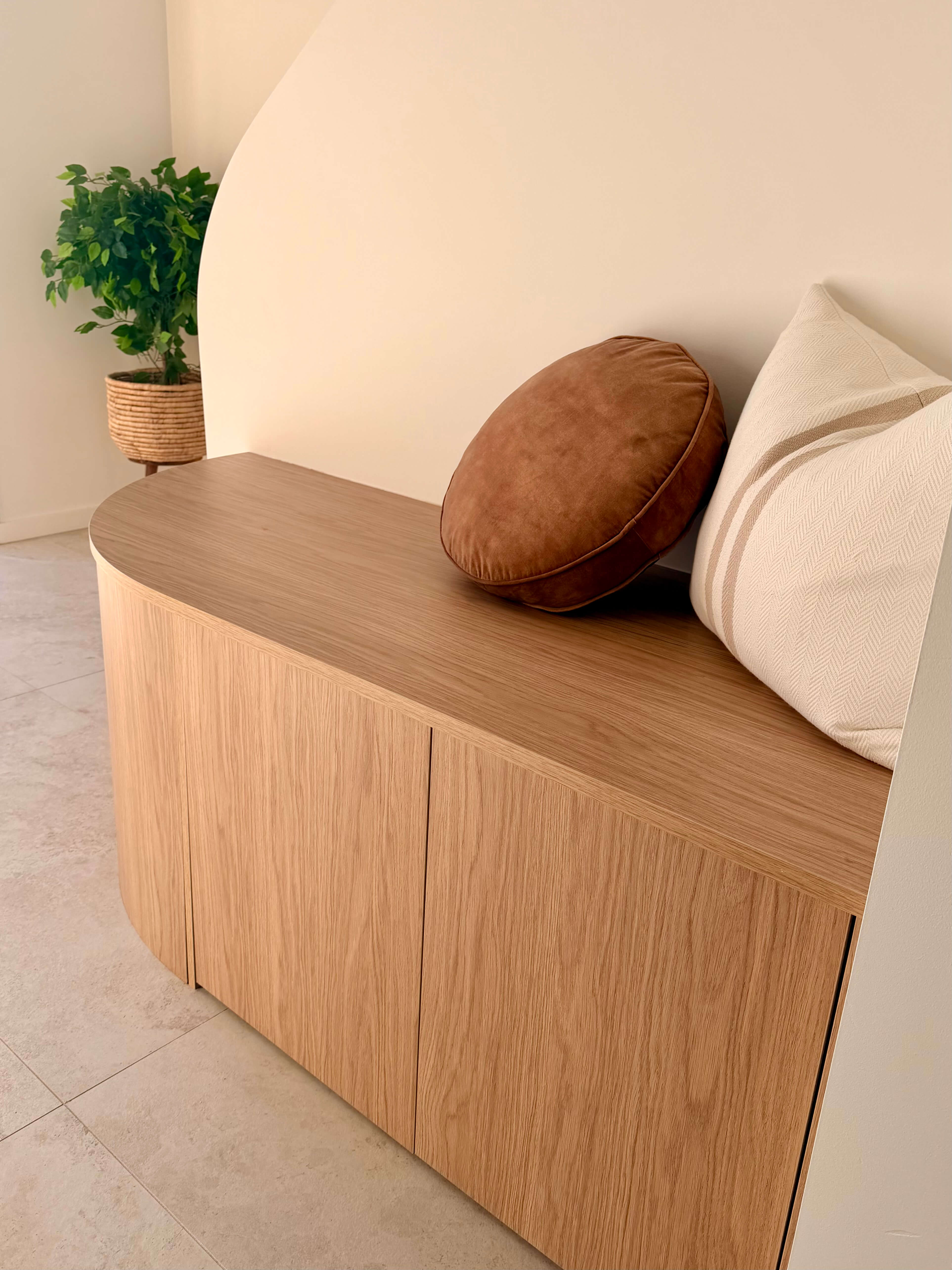 Luxury front entry featuring a curved custom bench seat, integrated shoe storage and handcrafted joinery.