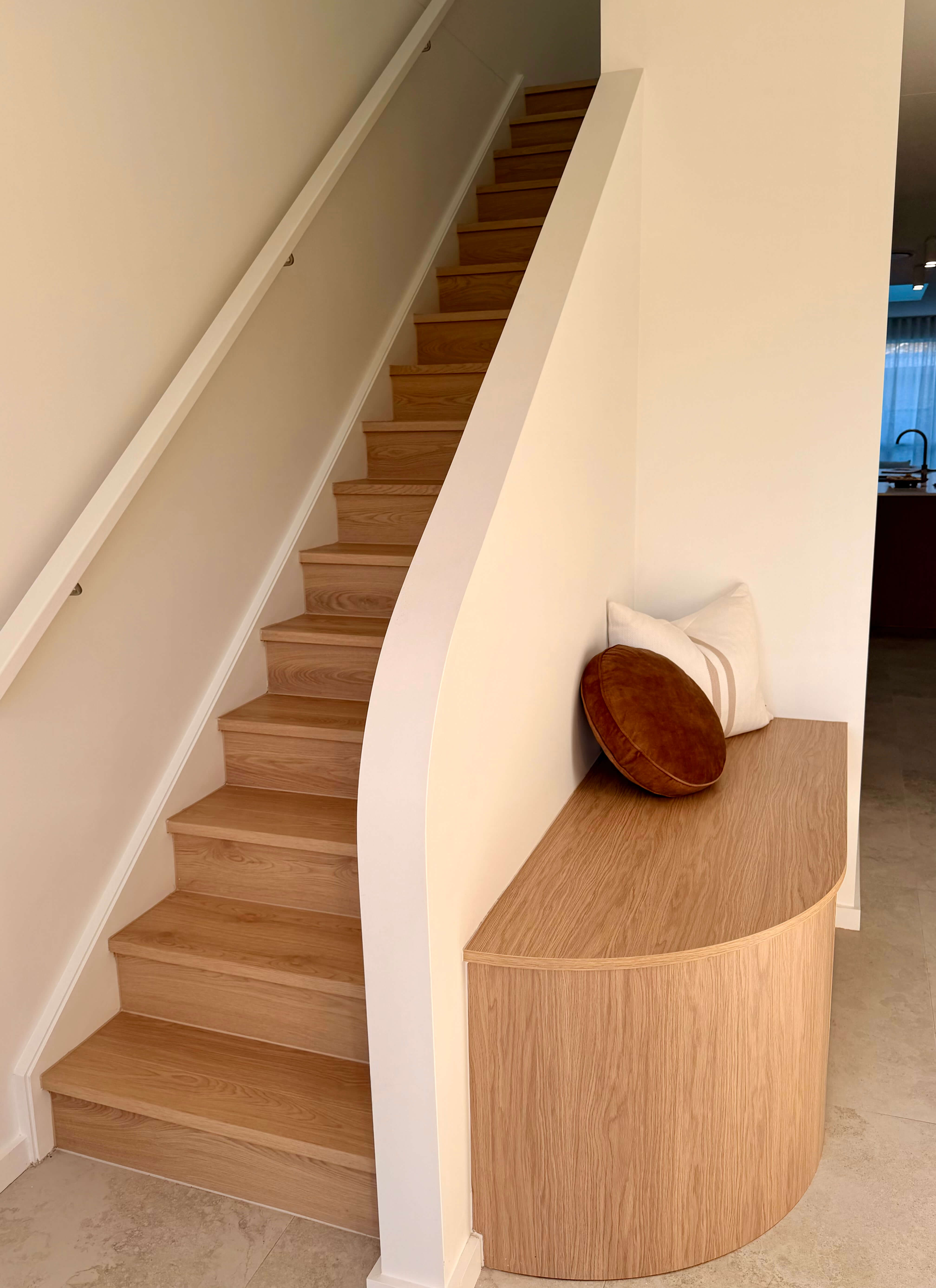 Curved custom shoe storage built into the side of the staircase, featuring sliding door cabinetry and bespoke joinery.
