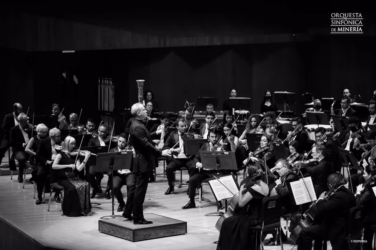 Black and white photo of an orchestra with Carlos Miguel Prieto at the center. Text in upper right of image reads, "Orquesta Sinfonica de Minería."
