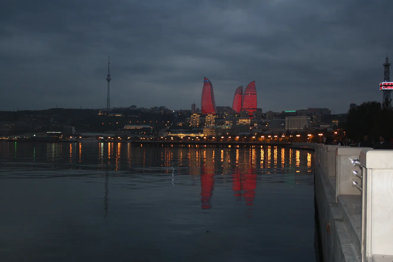 Baku’s Flame Towers, lit red at nightfall, reflected in the bay as seen from the seafront boulevard.
